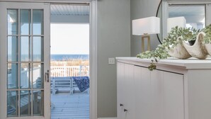 A room with a view of the beach, a white cabinet, and a lamp. - Waterfront Willoughby Oasis (Norfolk)