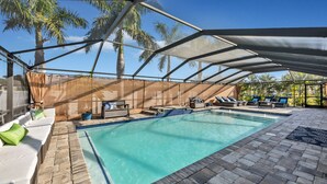 Piscina coberta com espreguiçadeiras e um espaço para sentar, cercada por palmeiras.