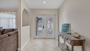 Um corredor com porta, um console com objetos decorativos e um sofá.