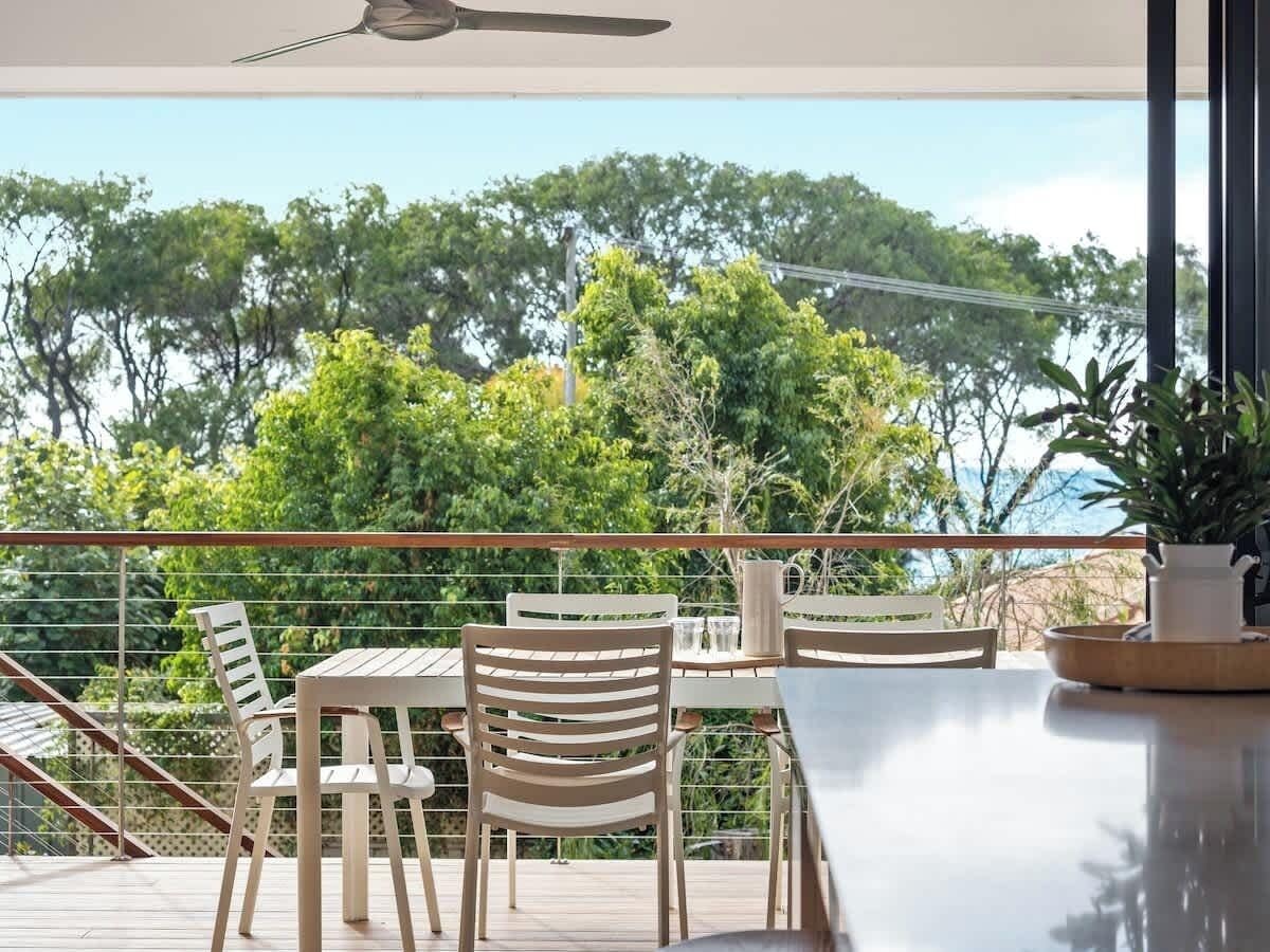 A balcony with a table and chairs, overlooking a forested area.