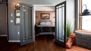 Un dormitorio con cama, ventana y puerta que da a otra habitación.