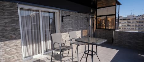Un balcón con puerta de cristal, una mesa y dos sillas.