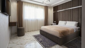 A modern hotel room with a large bed, a flat-screen TV, a wooden headboard, and a large window with curtains. - Immoka Apart-hotel (Tangier)