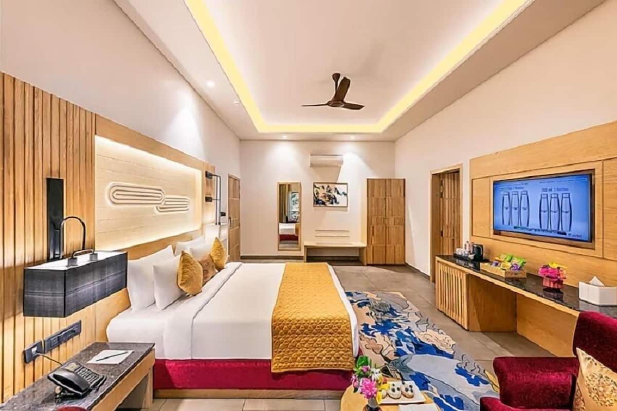 Una habitación de hotel moderna con una cama, un escritorio, un televisor y un ventilador de techo.