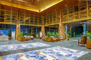 A spacious lobby with a high ceiling, large windows, and a central seating area with chairs and tables. - Ananta Spa & Resorts Jaipur (Jamwa Ramgarh)