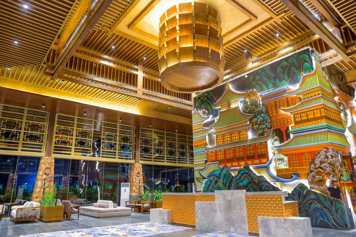 A lobby with a high ceiling, wooden beams, and a large mural of traditional architecture.