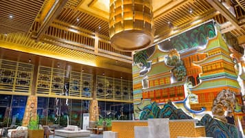 A lobby with a high ceiling, wooden beams, and a large mural of traditional architecture.