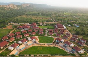 A residential area with multiple houses, a central open space, and a mountainous backdrop. - Ananta Spa & Resorts Jaipur (Jamwa Ramgarh)