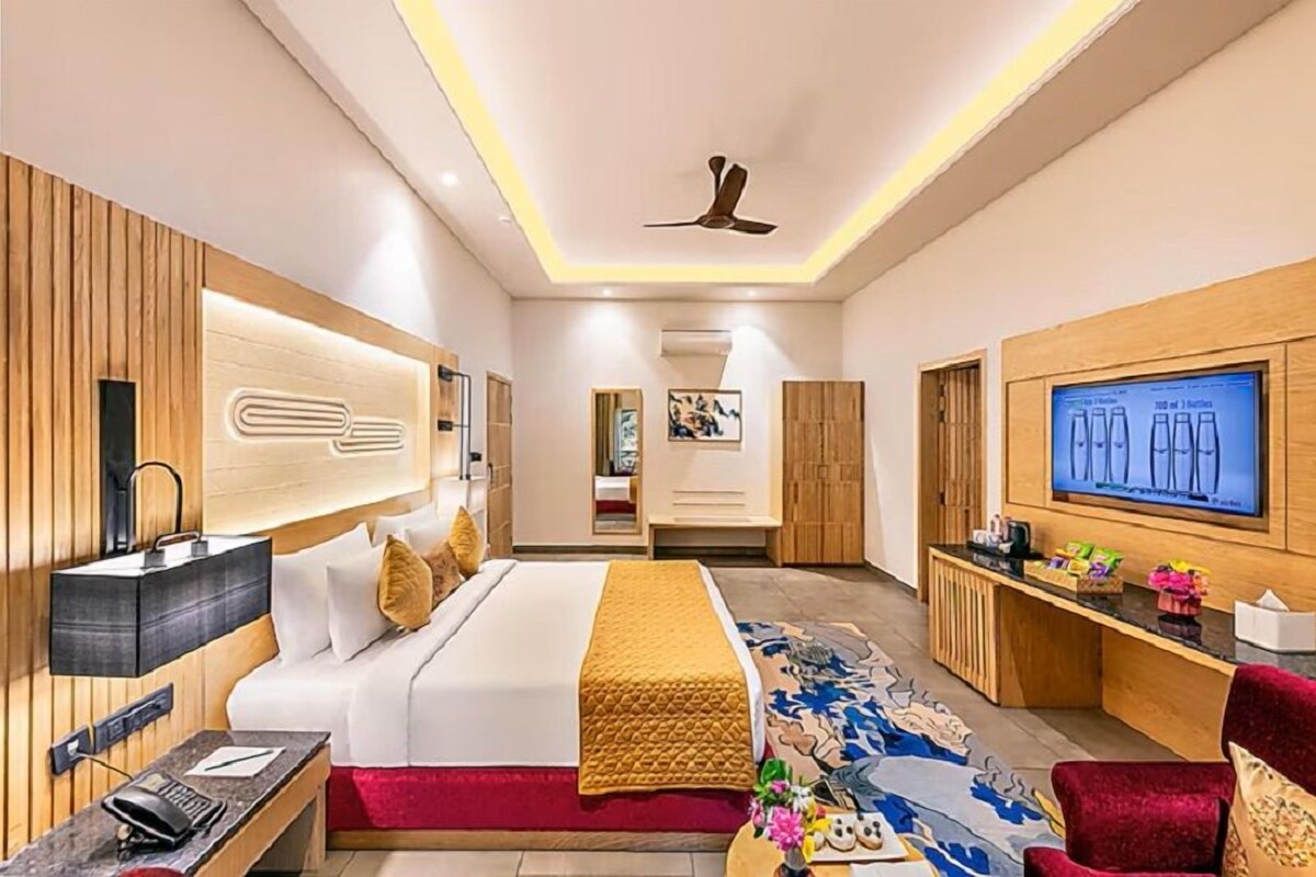 A modern hotel room with a bed, a desk, a TV, and a ceiling fan.