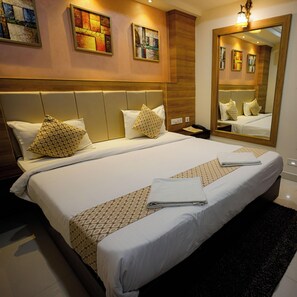 A hotel room with a large bed, two bedside tables, a mirror, and artwork on the walls. - M Square Hotel-hitec City (Hyderabad)