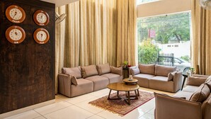 A living room with a sectional sofa, a coffee table, and a wall clock displaying time from four different countries.