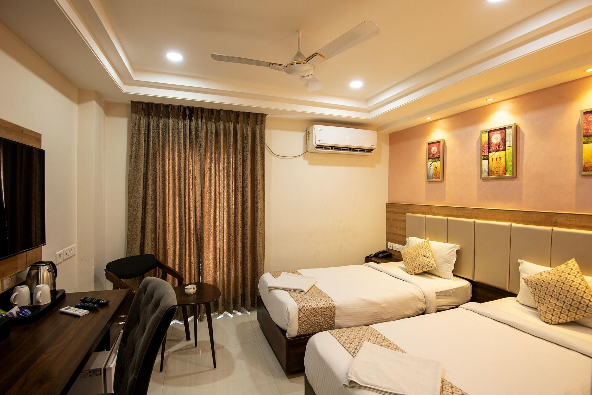 A hotel room with two beds, a desk with a chair, a television, and an air conditioning unit.