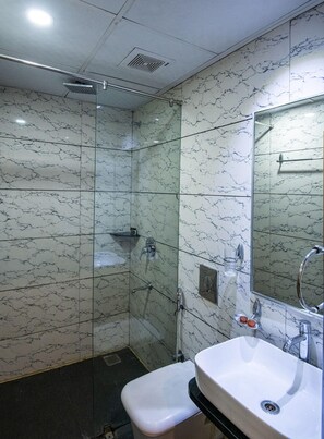 A bathroom with a glass shower enclosure, a white sink, and a mirror.