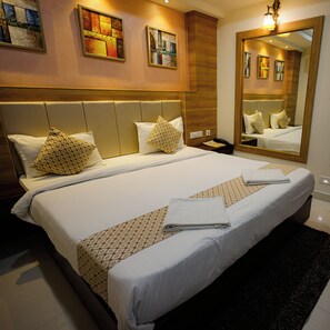 A hotel room with a large bed, two bedside tables, a mirror, and artwork on the walls. - M Square Hotel-hitec City (Hyderabad)