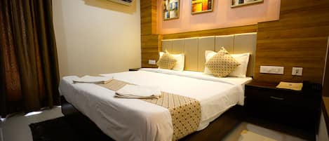 A modern hotel room with a large bed, a bedside table, an air conditioning unit, and artwork on the wall.