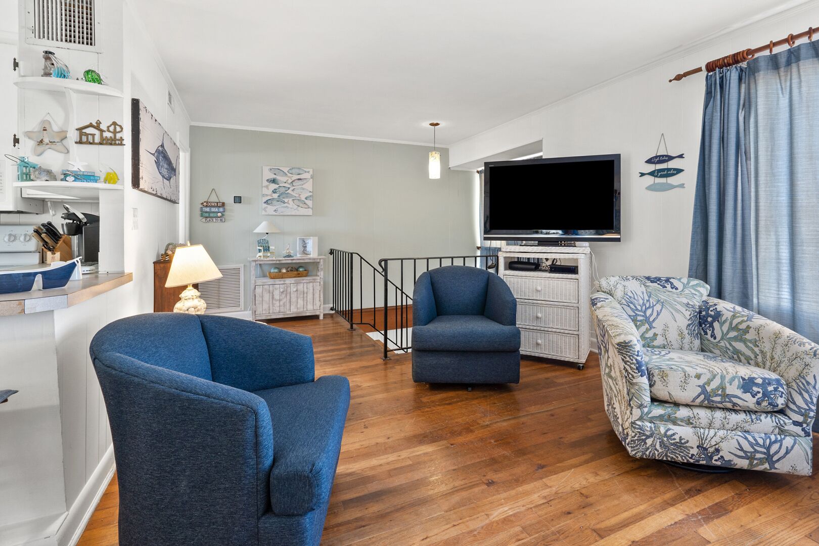 A modern living room with a flat-screen TV, two sofas, a small table, and a staircase.