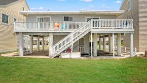 Une maison à deux étages dotée d’un patio couvert et d’un escalier menant à l’étage supérieur.