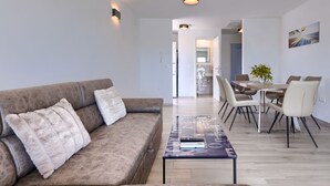 A modern living room with a brown leather sofa, a glass coffee table, and a dining area with white chairs and a wooden table. - Villa Galici by Interhome (Umag/Murine)