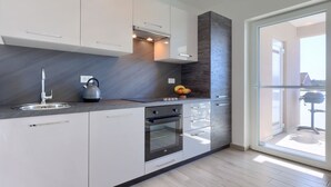 A modern kitchen with white cabinets, a stainless steel sink, a kettle, and a fruit bowl. - Villa Galici by Interhome (Umag/Murine)