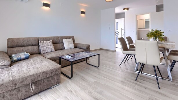 A modern living room with a sectional sofa, a coffee table, and a dining area with chairs and a table. - Villa Galici by Interhome (Umag/Murine)