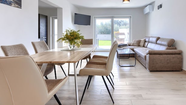 A modern living room with a dining area, a sofa, and a TV mounted on the wall. - Villa Galici by Interhome (Umag/Murine)