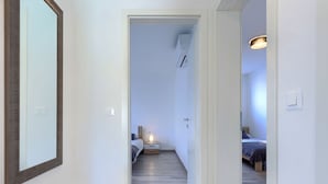 A narrow hallway with a wooden floor leading to a bedroom with a bed and a nightstand. - Villa Galici by Interhome (Umag/Murine)