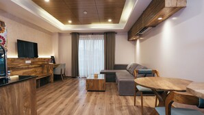 A modern living room with a wooden floor, a sofa, a coffee table, and a TV mounted on the wall. - Hotel Bhrikuti Tara (Kathmandu)