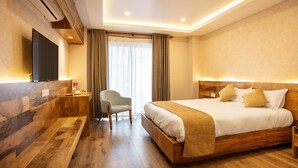 A modern hotel room with a wooden bed, a flat-screen TV, a bench, and a chair. - Hotel Bhrikuti Tara (Kathmandu)