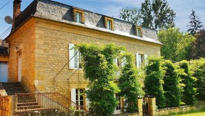 A stone house with a sloped roof, a small porch, and a staircase leading to the entrance. - Beautiful home in Groléjac with WiFi (Groléjac)