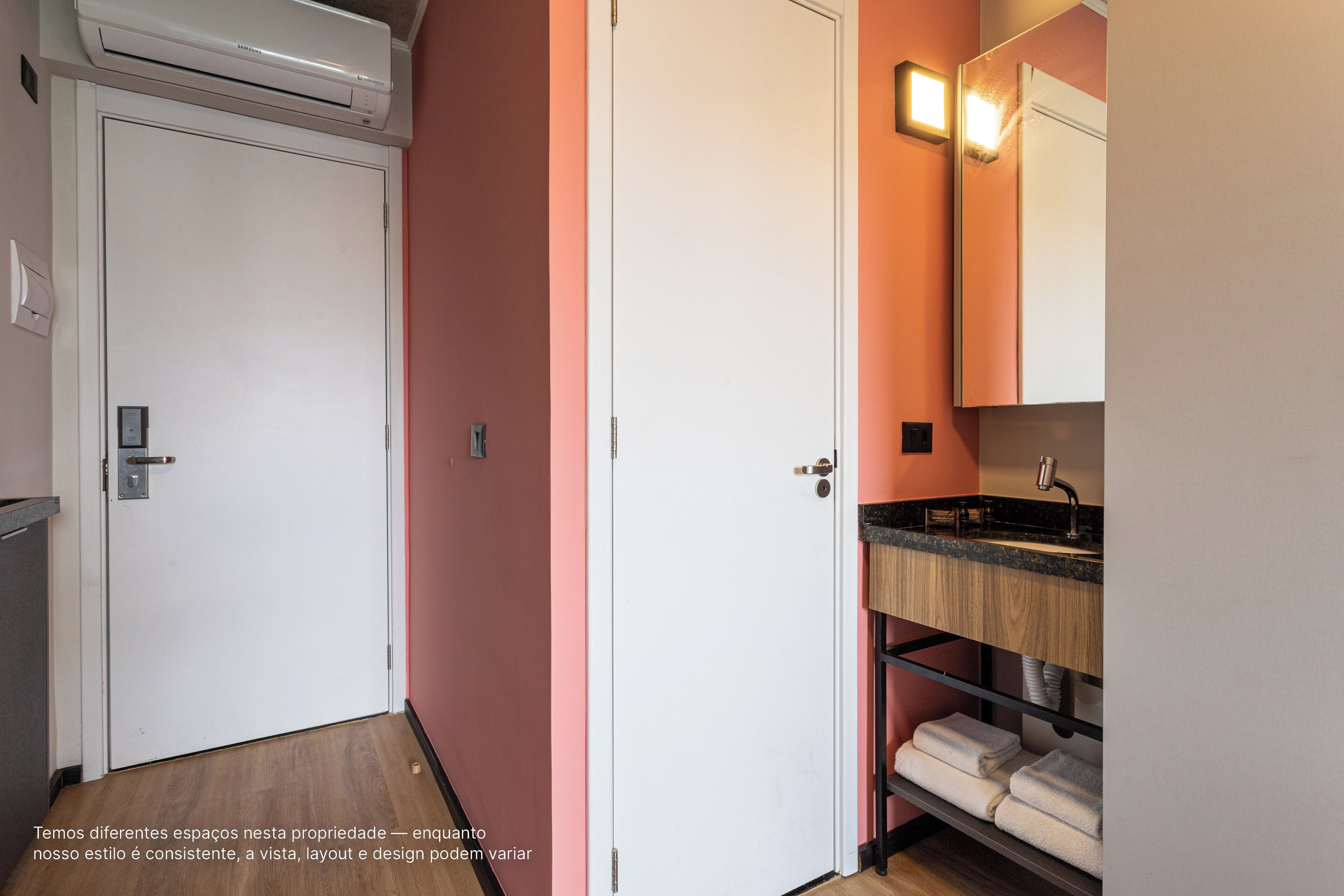 Ein Hotelzimmer mit weißer Tür, einem Badezimmer mit Holzanrichte und einem Handtuchhalter.