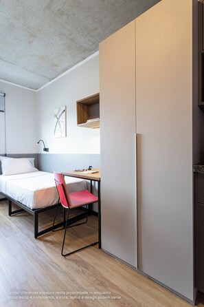 A bedroom with a bed, a desk, a chair, and a wardrobe. - Caza Noz by Viva - Apartamentos novos, com ótima estrutura e área comum próximo à USP e Butantã (São Paulo)