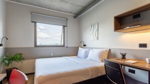 Habitación de hotel moderna con cama, escritorio, silla y vista al cielo a través de una ventana.
