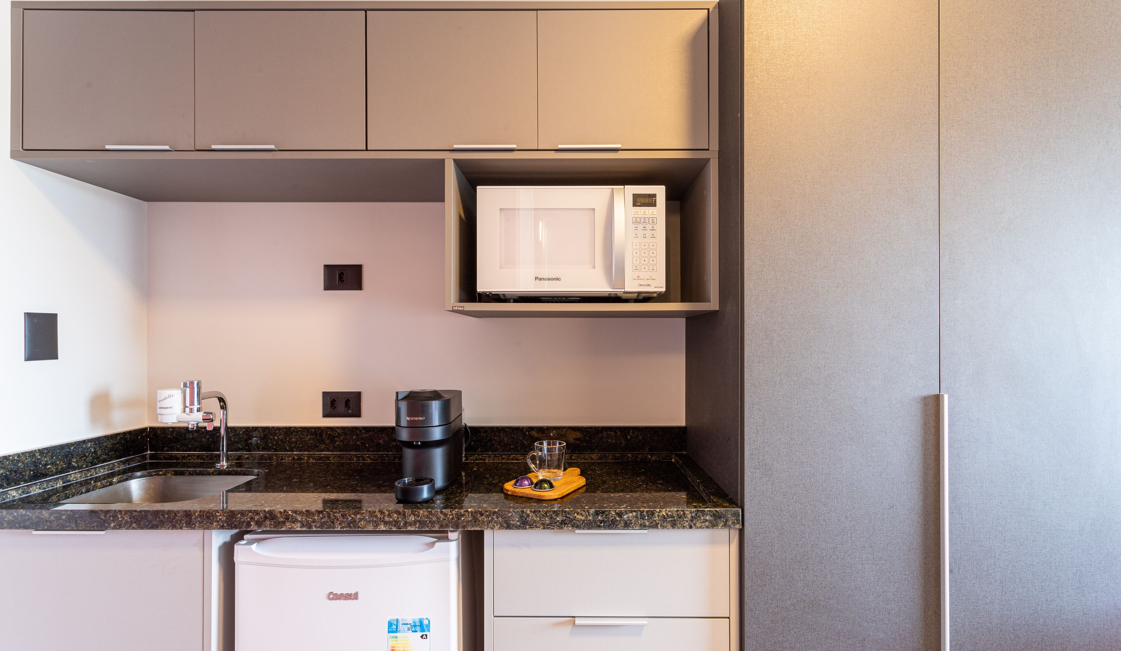 A compact kitchen with a built-in microwave, a coffee maker, and a dishwasher.