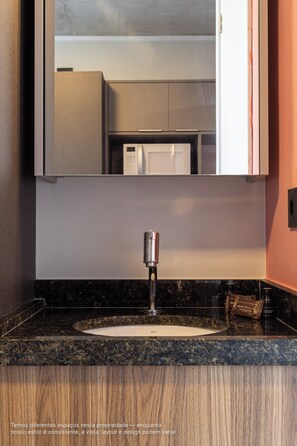 A bathroom with a sink, mirror, and cabinets. - Caza Noz by Viva - Apartamentos novos, com ótima estrutura e área comum próximo à USP e Butantã (São Paulo)