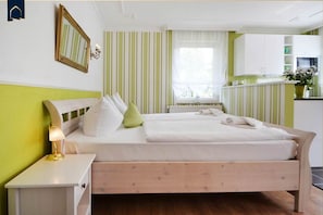 Un dormitorio ordenado con cama, mesita de noche, lámpara y ventana con cortinas.