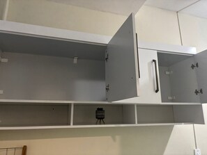 A room with white walls, a ceiling with a grid pattern, and a partially open cabinet with a handle. - Apartamento na Praia do Forte 😉 , Centro Cabo Frio - RJ 118 (Centro Cabo Frio)