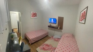 A room with two single beds, a small desk, a television, and a ceiling fan. - Apartamento na Praia do Forte 😉 , Centro Cabo Frio - RJ 118 (Centro Cabo Frio)