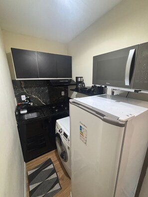 A compact kitchen with a washing machine, a coffee maker, and a microwave. - Apartamento na Praia do Forte 😉 , Centro Cabo Frio - RJ 118 (Centro Cabo Frio)