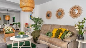 A modern living room with a beige sofa, round side tables, a green rug, and decorative sunburst mirrors on the wall. - Fuengirola Seaside Bliss: 3 BR with a View (Fuengirola)