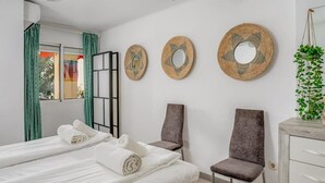 A hotel room with two beds, a chair, a dresser, and three wall-mounted mirrors. - Fuengirola Seaside Bliss: 3 BR with a View (Fuengirola)