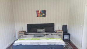 Una camera da letto con un letto grande, due comodini, un tavolino e un quadro astratto dai colori vivaci appeso al muro.