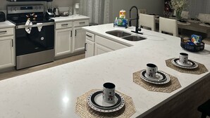 Una cocina moderna con armarios blancos, electrodomésticos de acero inoxidable y una isla central con individuales.