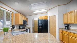 A kitchen with granite countertops, wooden cabinets, a black refrigerator, a microwave, and a coffee maker. - Big Parking Lot, Pets Invited, Fenced Farm Home (Kennewick)
