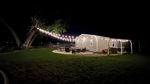 A house with a covered patio area, outdoor furniture, and string lights. - Big Parking Lot, Pets Invited, Fenced Farm Home (Kennewick)
