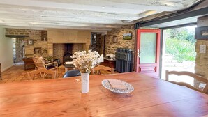 A rustic dining area with a wooden table, chairs, a vase with flowers, and a stone wall with a fireplace. - Beautiful home in St Paul La Roche (St Paul La Roche)