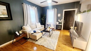 A living room with a beige sofa, a white armchair, a coffee table, and a fluffy rug. - Tranquil Tremont-Stay 3 nights & Enjoy 25% off 4th night (Cleveland)