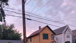 A residential street with houses, a colorful mural on a fence, and a parked car. - Tranquil Tremont-Stay 3 nights & Enjoy 25% off 4th night (Cleveland)