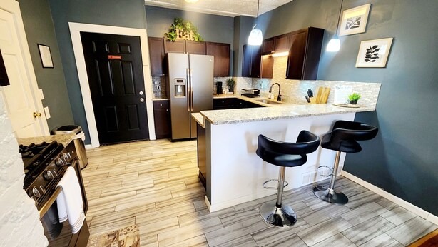 A modern kitchen with a central island, bar stools, a refrigerator, and a 'No Smoking' sign on the door. - Tranquil Tremont-Stay 3 nights & Enjoy 25% off 4th night (Cleveland)