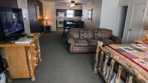 A living room with a television, a wooden desk, a brown leather sofa, and a quilted bed frame. - Studio Style Condo with Full Kitchen and Spacious Deck (Estes Park)