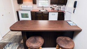 A kitchen with a central island, two stools, a microwave, a refrigerator, and a sink. - Studio Style Condo with Full Kitchen and Spacious Deck (Estes Park)